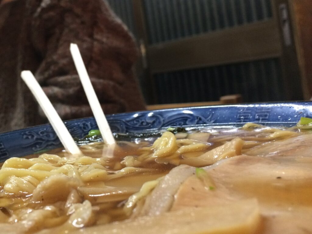 青い縁の丼に入ったチャーシュー麺。奥にガラスの引き戸　／　02_yabusoba_2017.jpg