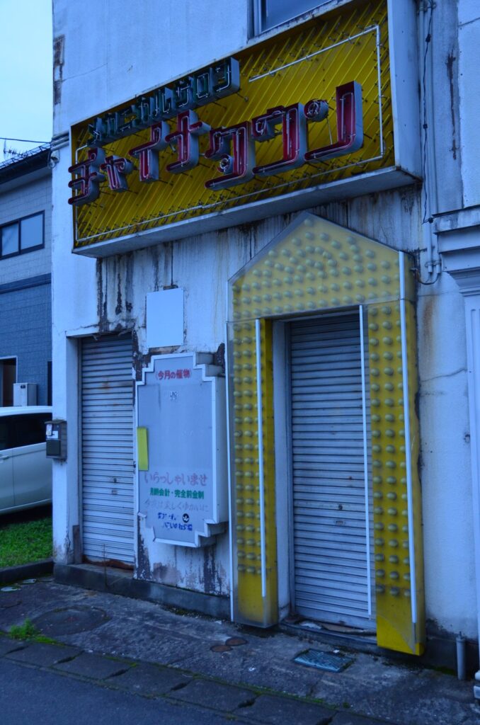 黄色いネオン看板と電球の縁取りが残る、シャッターの閉じた店　／　06_shimatta_neon.jpg